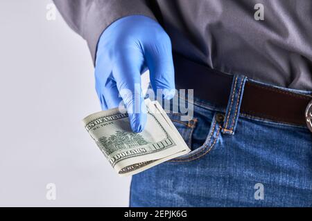 uomo che indossa camicia, jeans blu e guanti protettivi in lattice. Dare denaro gesto. Protezione in tempo pandemico Foto Stock