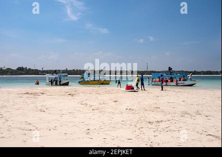 Una barca con fondo di vetro ormeggiata da una bassa riva di sabbia con persone sulla sabbia, Diani, Kenya Foto Stock