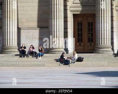 Giovani seduti su gradini nel centro della città, Dundee