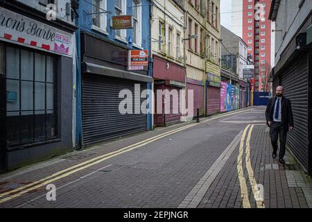 LARNE, IRLANDA DEL NORD - Febbraio, 24 : UN uomo cammina attraverso i negozi chiusi a causa della pandemia COVID-19 a Larne . Foto Stock