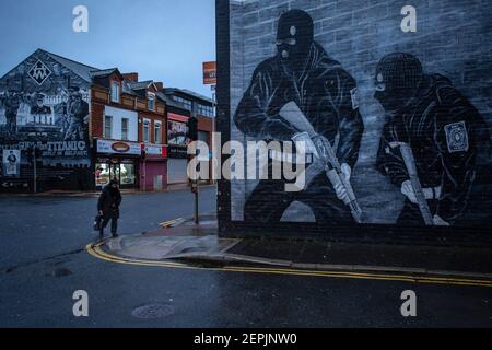 BELFAST, IRLANDA DEL NORD - Febbraio, 23: Una donna passa davanti a un murale paramilitare lealista sulla strada Newtownards il 23 febbraio 2021 a Belfast. Foto Stock