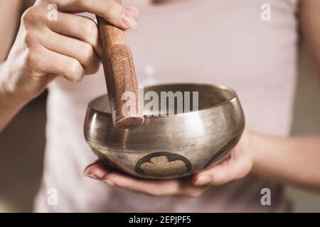 Una donna che pratica yoga gioca su una ciotola tibetana, primo piano Foto Stock