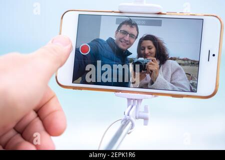 Coppia prende un selfie su uno smartphone. I blogger girano video sullo smartphone. Foto Stock