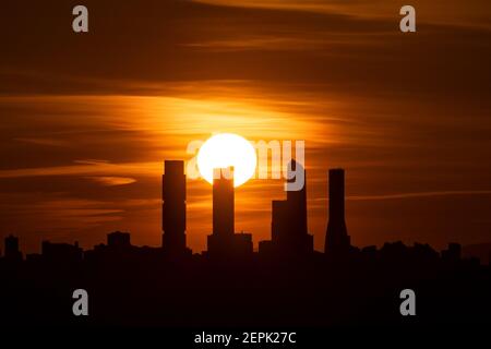 Madrid, Spagna. 27 Feb 2021. Il sole tramonta dietro lo skyline con la Four Towers Business Area (CTBA) durante un pomeriggio di primavera con il clima caldo. Credit: Marcos del Mazo/Alamy Live News Foto Stock