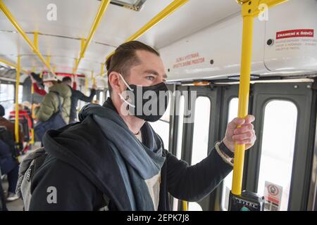 Un uomo che indossa una maschera medica su un tram di Praga durante la pandemia del coronavirus. Foto Stock