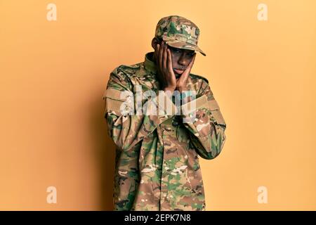Giovane afroamericano che indossa uniforme esercito mani stanche che coprono il viso, la depressione e la tristezza, sconvolto e irritato per il problema Foto Stock