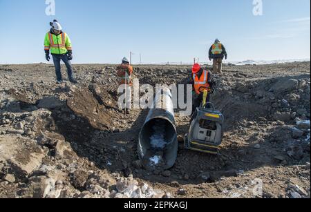 Quattro lavoratori maschi indigeni che installano il culvert durante la costruzione invernale dell'autostrada Inuvik-Tuktoyaktuk, territori del Nord-Ovest, artico del Canada. Foto Stock