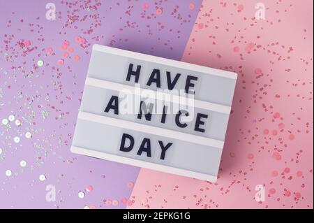 Buona giornata - testo sul display light box su sfondo viola e rosa. Foto Stock