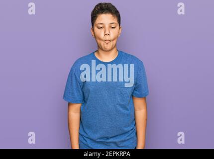 Ragazzo ispanico adolescente che indossa abiti casual facendo viso di pesce con labbra, pazzo e comico gesto. Divertente espressione. Foto Stock