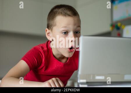 Boy 6-10 completa le lezioni scolastiche e i compiti online in cucina, guardando il computer tablet. Il concetto di istruzione a distanza. Rimani a casa Foto Stock