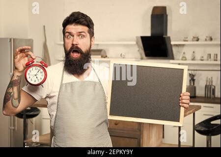 Chef al lavoro. Uomo bearded sorpreso in grembiule cuoco. Ora di pranzo. Allarme orario per la dieta e lo stile di vita sano. La migliore offerta di sempre. Cucina e cucina. Spazio per fotocopie. Cucina, menu per cena da chef esperto. Foto Stock