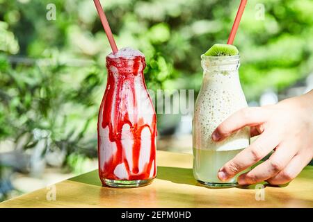 Due milkshake afferrati con una mano su un tavolo di legno Foto Stock