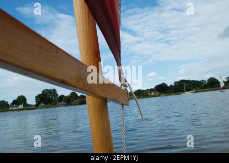 Primo piano del ligneo (braccio) su un piccolo gommone con vela rossa, corde bianche e albero di legno. Foto Stock