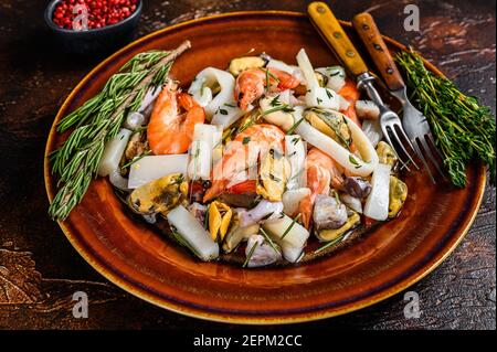 Cocktail di pesce marino con gamberi, gamberi, cozze, calamari e polpi su un tagliere. Sfondo di legno scuro. Vista dall'alto Foto Stock