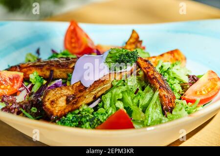 Insalata di verdure e pollo su piatto blu Foto Stock