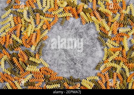 Colorata pasta di fusilli crudi sparsa su un tavolo di marmo Foto Stock