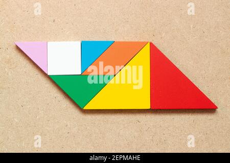 Puzzle tangram a colori a forma di parallelogramma su sfondo di legno Foto Stock