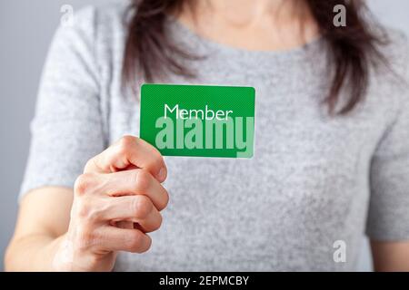 Una giovane donna caucasica sta tenendo una carta verde che dice membro su di essa. Immagine personalizzabile con spazio per il testo da inserire. Essere un membro, Foto Stock