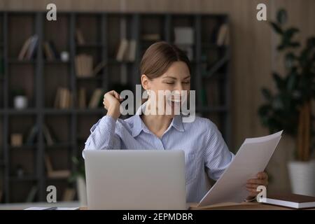 La giovane donna eccitata trionfa leggendo le notizie nella lettera Foto Stock