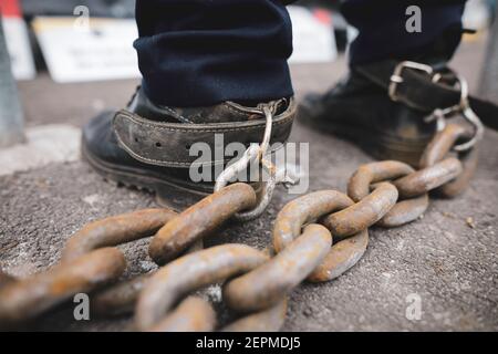 Profondità di campo poco profonda (fuoco selettivo) dettagli di un poliziotto che ha legato una catena metallica arrugginita ai suoi piedi durante una protesta a Bucarest. Foto Stock