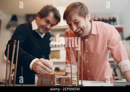 Architetto caucasico adulto giovane e anziano che lavora al tavolo con progetto, disegno di progetto e la disposizione della costruzione presso l'ufficio architettonico. Foto Stock