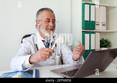 Dall'alto di tatuista maschile irriconoscibile utilizzando la macchina e la fabbricazione tatuaggio sul braccio del cliente di raccolto in salone Foto Stock