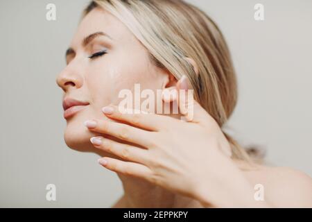 Olio cosmetico gelatina reale applicando con pipetta sulla faccia di giovane donna Foto Stock