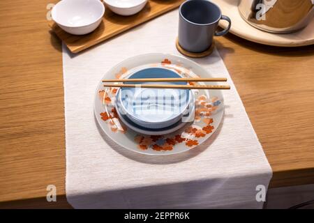 Tavolo orientale. Blu chiaro e con ciotole di soia vuote, tazze e bacchette di bambù Foto Stock