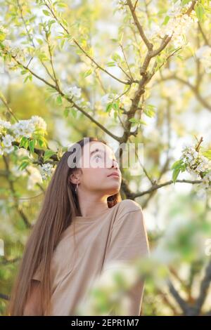 Bella ragazza teen con fiori di mela in fiore. Felice bambino carino divertirsi all'aperto al tramonto. Foto Stock