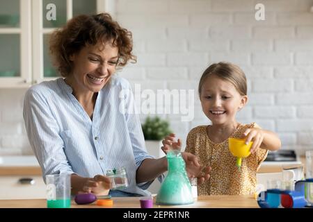 Madre emozionale e bambino figlia facendo esperimenti chimici in cucina Foto Stock