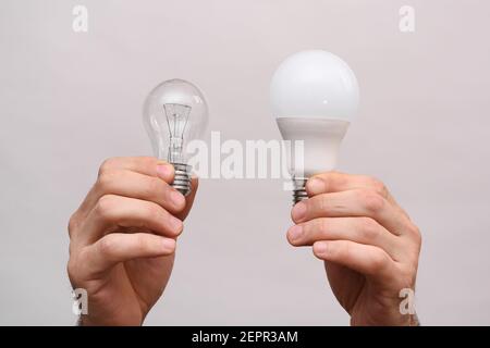 Lampadina a incandescenza e lampadina a LED nelle tue mani. Foto Stock