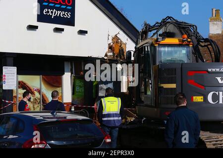 Dymchurch, Kent, Regno Unito. 28 febbraio 2021. I ladri immolati hanno tentato un’audace incursione su questo Tesco express in via Dymchurch Hugh avendo guidato un escavatore cingolato Volvo ECR235E nelle prime ore del mattino in una tentata rapina da cashpoint. Un negozio di fronte è stato lasciato con 'danno significativo' in un tentativo fallito di strappare una macchina di cassa con un digger, la polizia dice. Un angolo dell'edificio si trova in tatters. Si credeva che il digger fosse stato rubato da Dymchurch Beach. Photo Credit: Paul Lawrenson/Alamy Live News Foto Stock