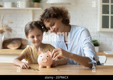 Amichevole mamma e figlia capretto prosperare monete in piggybank Foto Stock