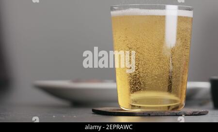 versare il sidro di mela in un bicchiere sul piano di cemento con finestra sullo sfondo, foto ampia Foto Stock