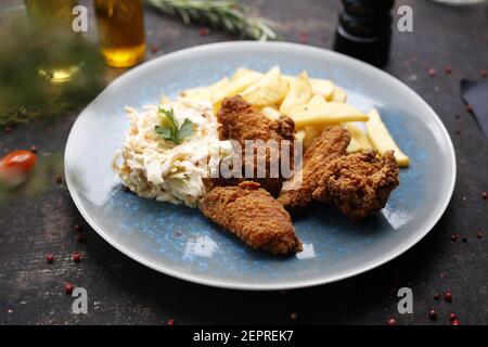 Bocconcini di pollo con patatine fritte e insalata di cavoli. Cena fast food. Il piatto finito servito su un piatto. Proposta di servizio, fotografia culinaria. Foto Stock