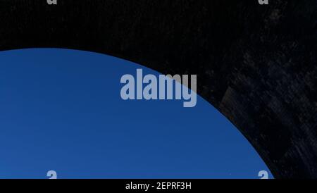 Cielo blu luminoso con arco grigio scuro sopra con copyspace Foto Stock