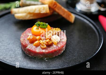 Tartare di manzo con tuorlo, funghi sottaceto e senape. Antipasto tradizionale. Servire il piatto. Foto Stock