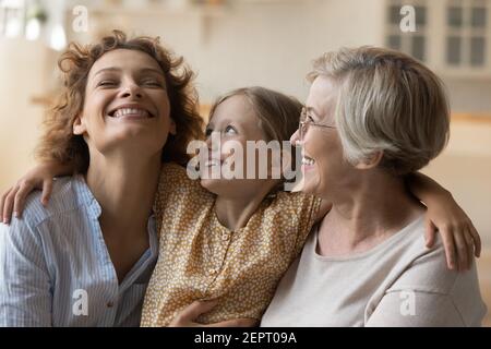 Famiglia amorevole di tre diverse età femmine abbraccio sul divano Foto Stock