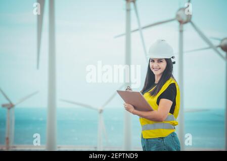 l'ingegnere femminile adulto supervisiona i pannelli solari e mulini a vento in un energia rinnovabile complesso Foto Stock