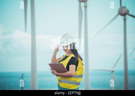 l'ingegnere femminile adulto supervisiona i pannelli solari e mulini a vento in un energia rinnovabile complesso Foto Stock