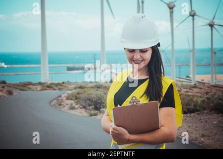 l'ingegnere femminile adulto supervisiona i pannelli solari e mulini a vento in un energia rinnovabile complesso Foto Stock