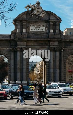 Madrid, Spagna - 28 febbraio 2021: Pedoni che indossano la maschera che attraversa di fronte alla famosa porta di Alcala in Independence Place, Madrid Foto Stock