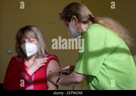 Apolda, Germania. 28 Feb 2021. Anke Mühlberg (l), dipendente di un asilo, riceve la vaccinazione Corona con il farmaco di AstraZeneca da Sylvia Baumbach presso il centro di vaccinazione di Apolda. Si prevede che oggi, presso i centri di vaccinazione, un totale di 5,350 dipendenti delle scuole elementari e speciali e degli asili della Turingia riceverà la prima vaccinazione a Corona. Credit: Michael Reichel/dpa-Zentralbild/dpa/Alamy Live News Foto Stock