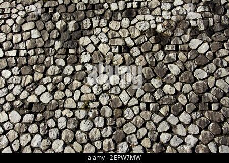 Pareti in pietra testurizzata con varie forme e dimensioni di pietre in una disposizione naturale che mette in risalto diverse tonalità Foto Stock