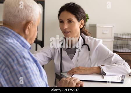 Primo piano sorridente medico confortante paziente maturo, condividendo buone notizie Foto Stock