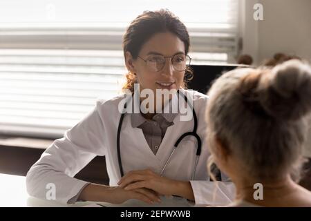 Primo piano sorridente dottore che indossa occhiali consultando paziente maturo Foto Stock