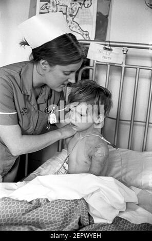 Ospedale Ward Cardiff per bambini. Infermiera che si prende cura del bambino appena fuori dell'intervento chirurgico Foto Stock