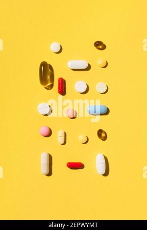 Compresse multicolore, pillole, capsule pattetn su sfondo giallo, spazio di copia. Mucchio di varie compresse e pillole di medicina assortite, vitamina e nurri Foto Stock