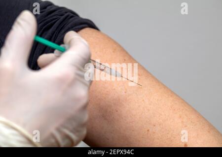 Vaccinazione con una siringa nella parte superiore del braccio Foto Stock