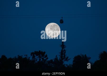 Santiago, Metropolitana, Cile. 28 Feb 2021. La luna piena di febbraio, chiamata Luna di neve, si pone dietro una funivia turistica a Santiago. Credit: Matias Basualdo/ZUMA Wire/Alamy Live News Foto Stock